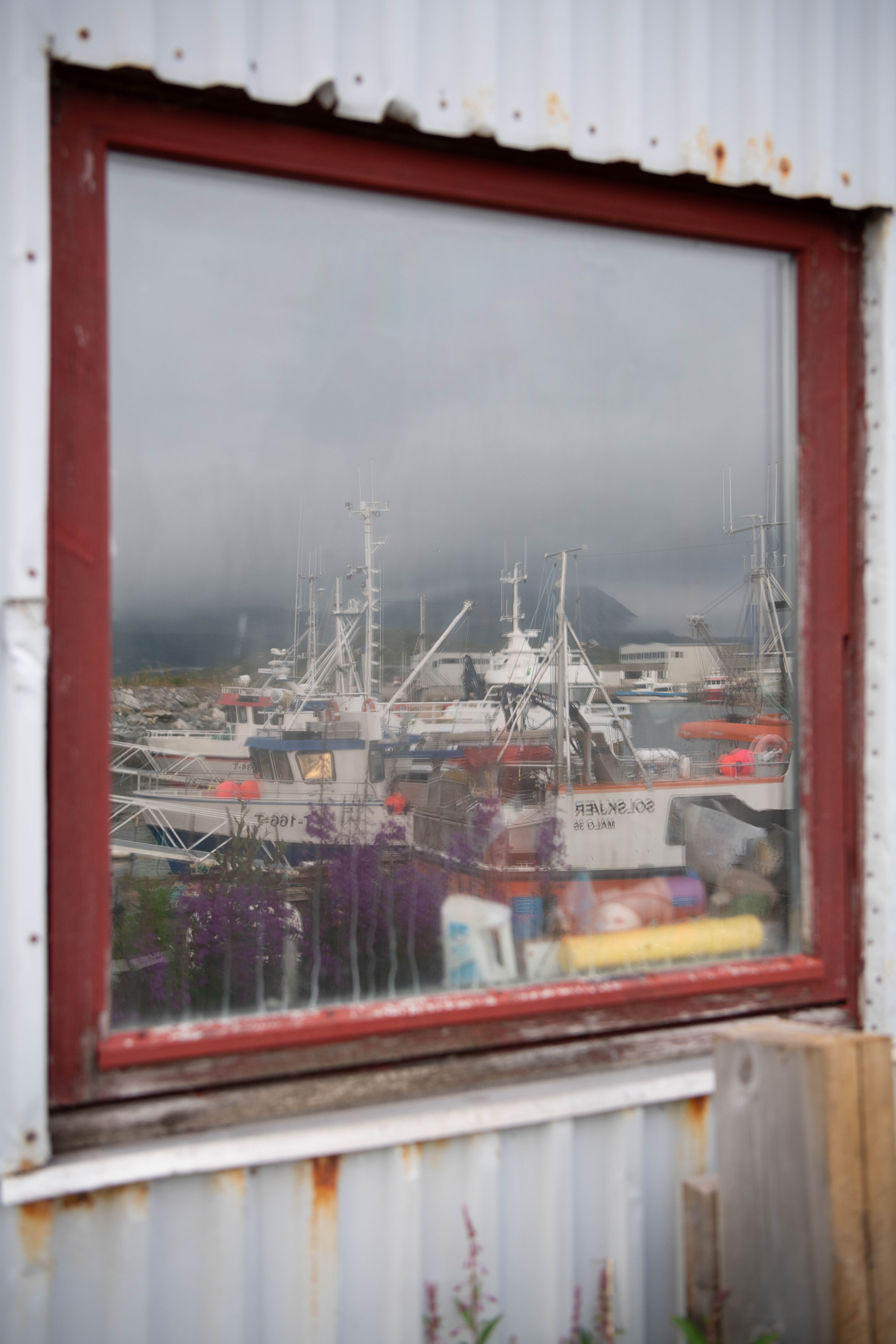 A color photograph of fishing boats reflected in a window of a building